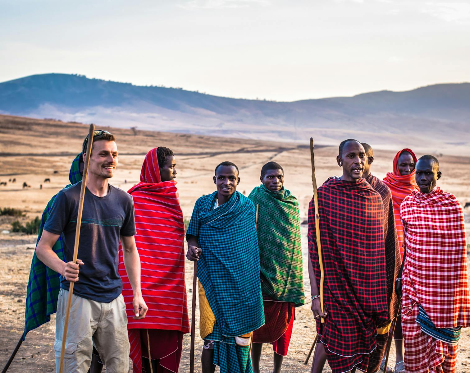 Un voyageur rejoint les membres de la tribu Masaï lors d'une journée ensoleillée dans un paysage africain ouvert.